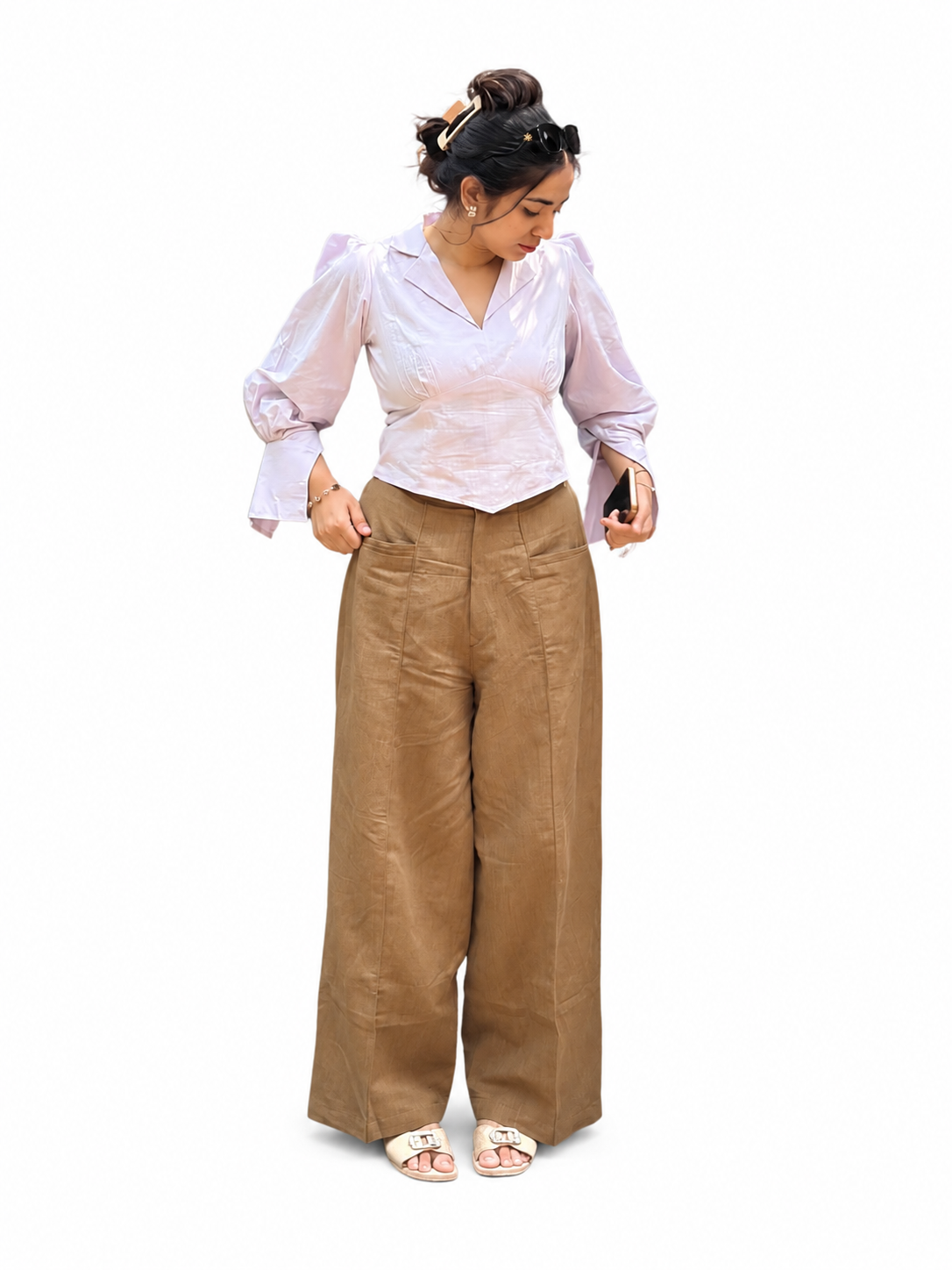 A woman modeling a Ash pink long-sleeve blouse with puffed sleeves and high-waisted, wide-leg brown trousers, standing against a plain background.