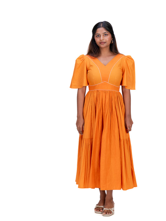 A woman modeling a bright Pomo orange midi dress with puff sleeves, a V-neckline, and white contrast stitching details, set against a plain white background.