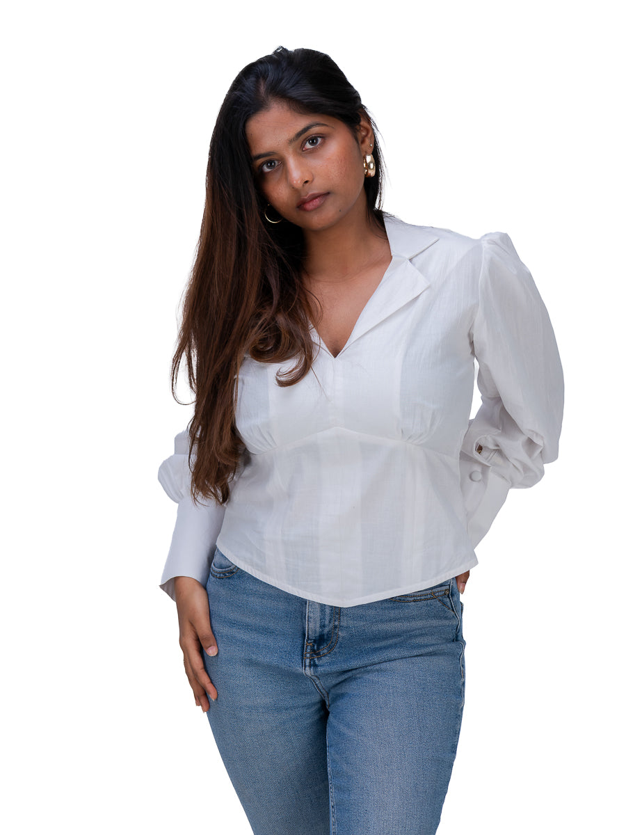 A woman modeling a White long-sleeve blouse with puffed sleeves and a V-neckline, paired with blue jeans, against a plain white background.