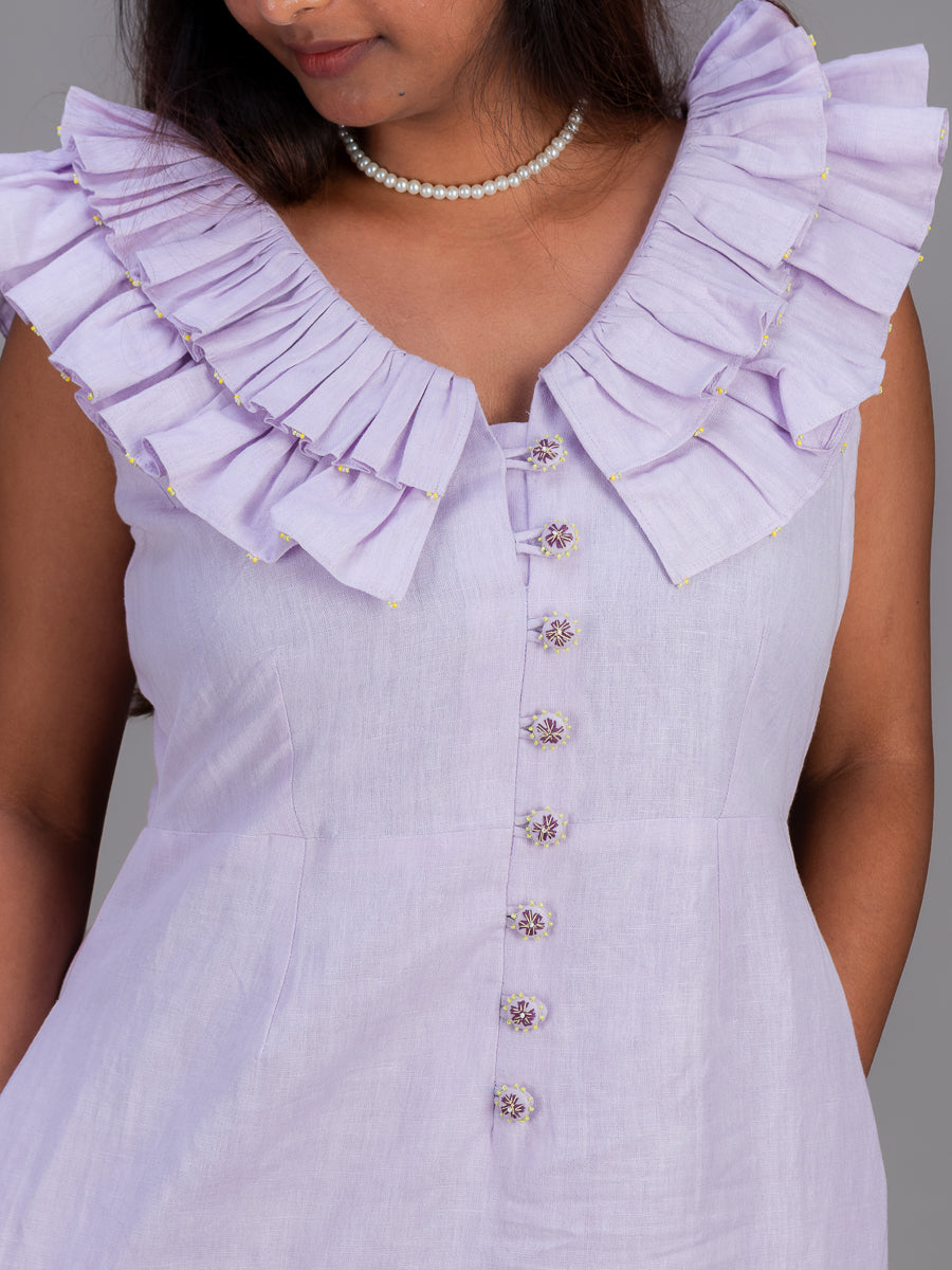 A close-up of a woman wearing a Cherry Pink sleeveless top with a large layered ruffle collar and decorative buttons down the front.