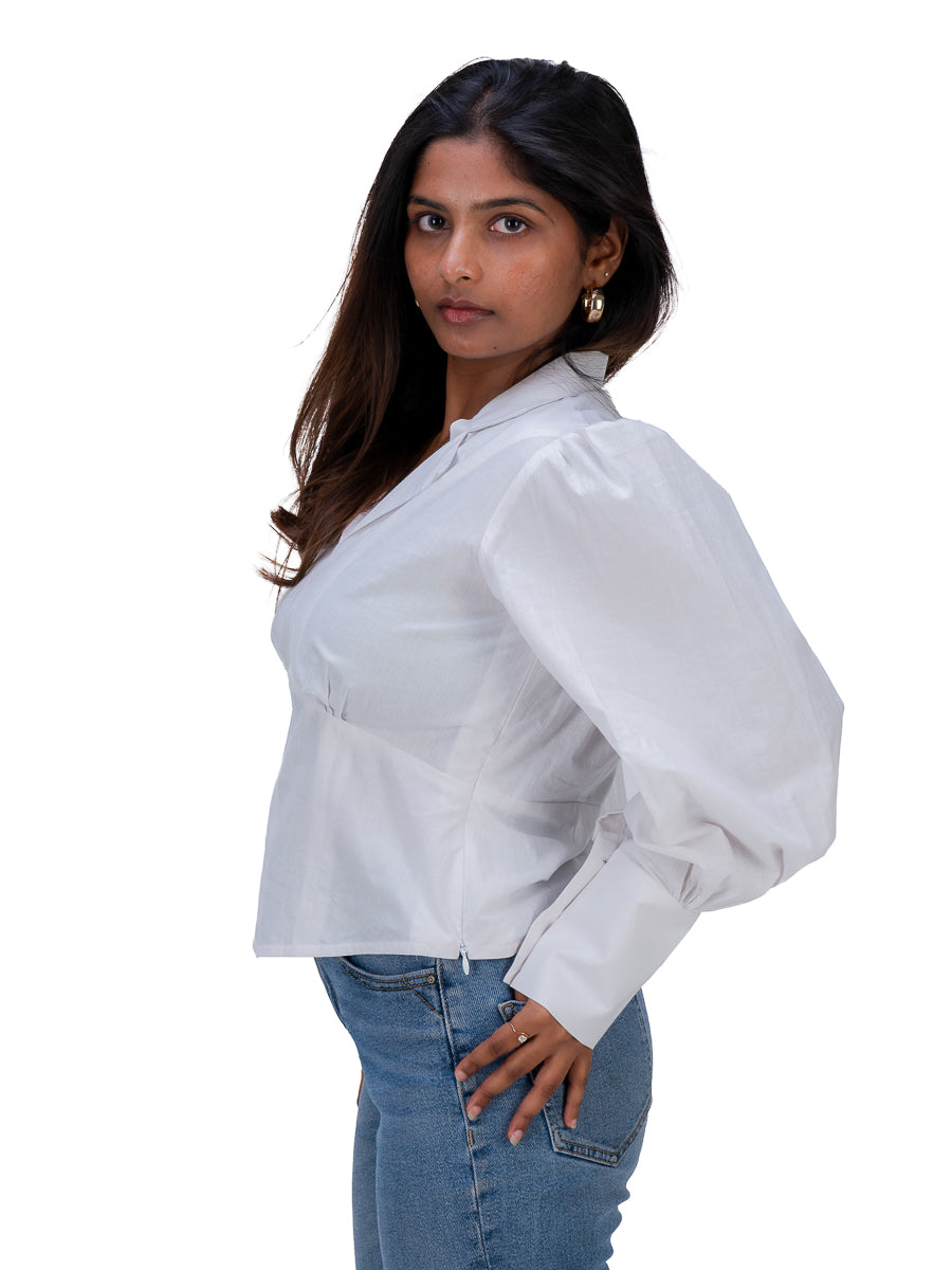 A woman wearing a White long-sleeve blouse with voluminous balloon sleeves and blue jeans, photographed against a plain white background.