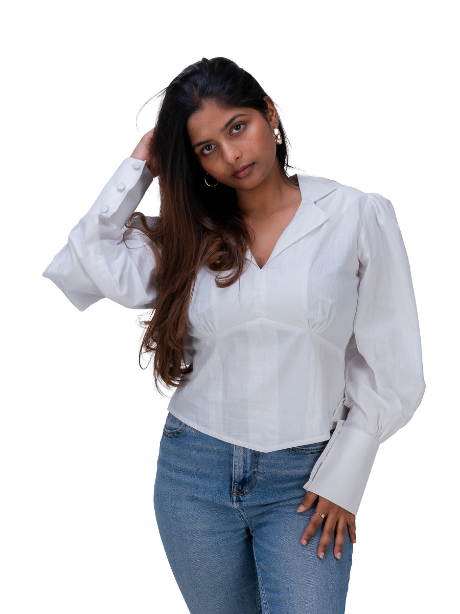 A woman modeling a White long-sleeve button-up blouse with a V-neck and chest pocket, paired with blue jeans, against a plain white background.