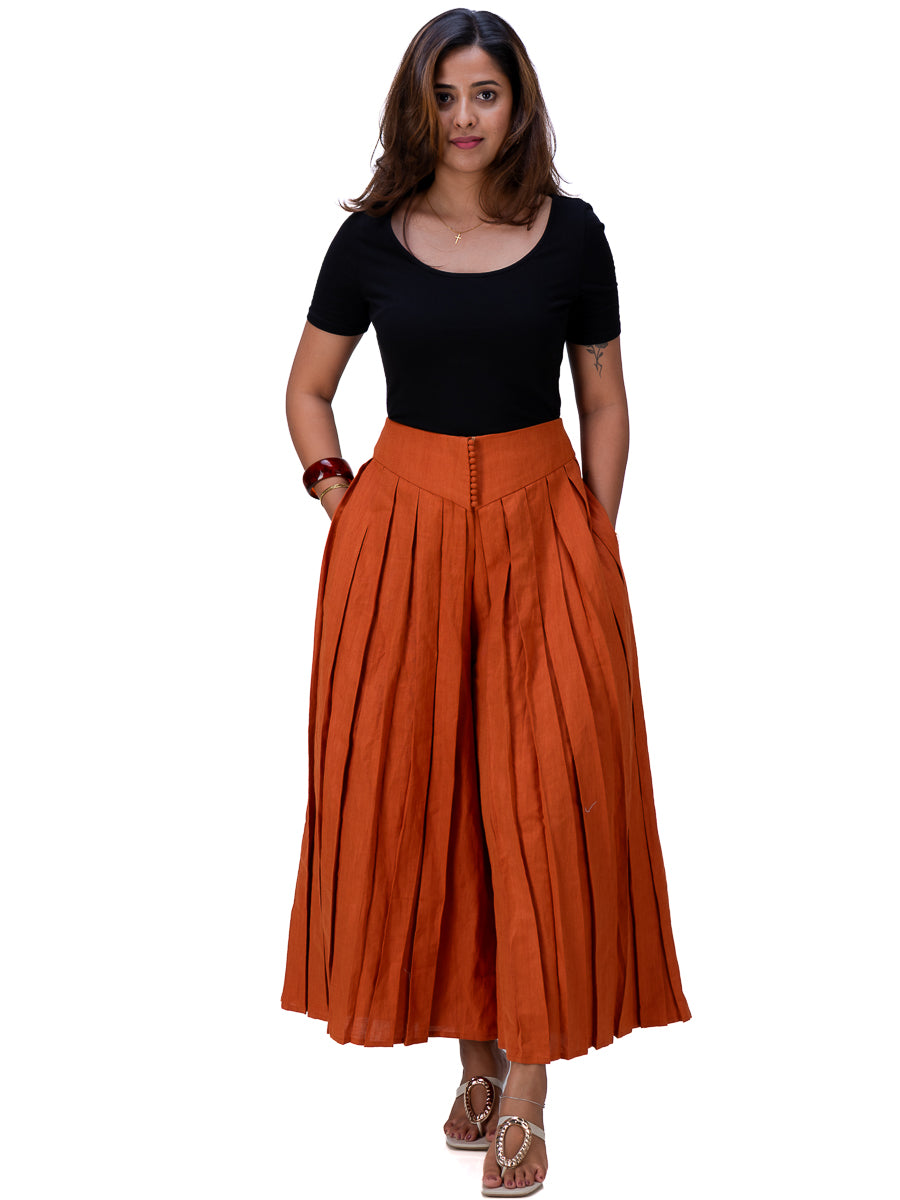 A woman modeling a black short-sleeve scoop-neck top paired with a high-waisted, wide-leg pleated maxi skirt in Brazil Brown, set against a plain white background.