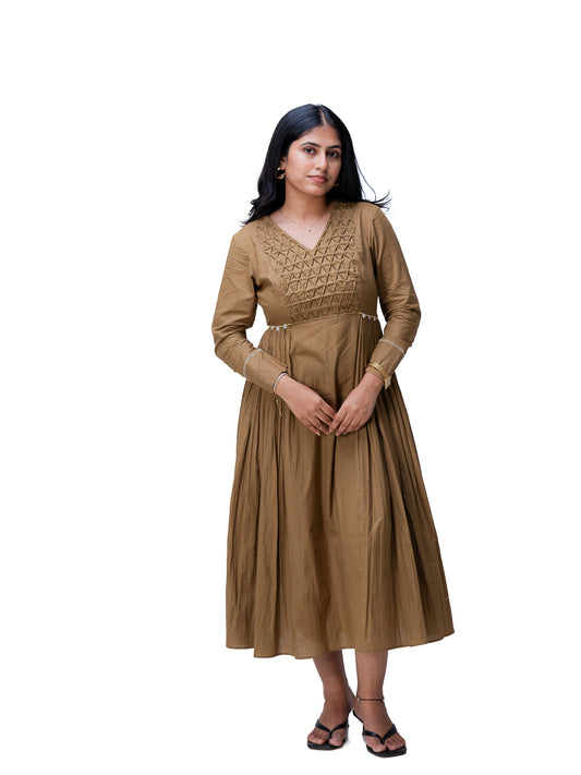 A woman modeling a long-sleeved Oak Brown midi dress with a textured embroidered yoke and a pleated skirt, standing against a plain white background.