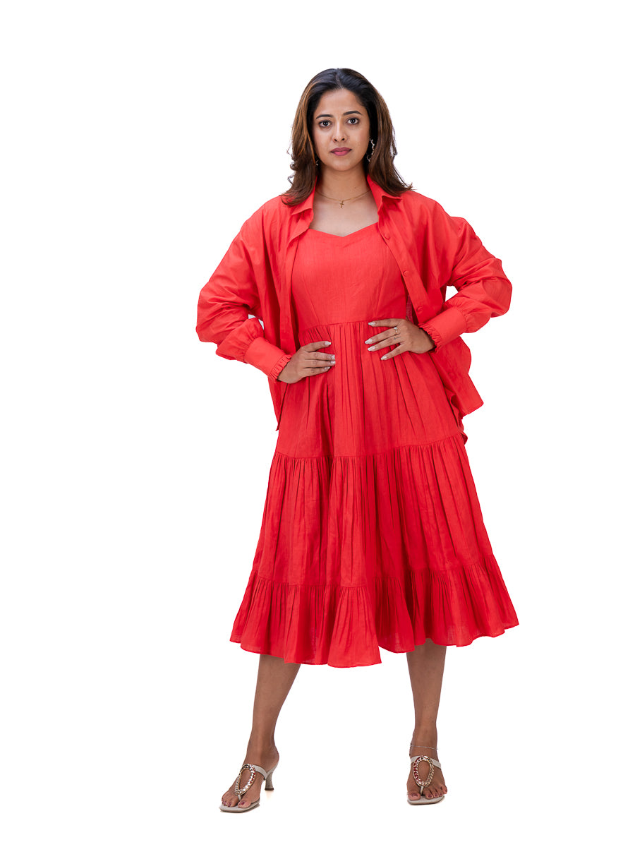 A woman modeling a Madder Red tiered midi dress with a matching long-sleeve button-up shirt jacket, paired with brown heeled sandals, against a plain white background.