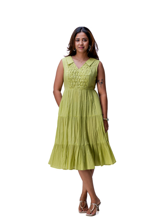 A woman modeling a sleeveless tiered midi dress in a light Dahlia Green color, standing against a plain white background.