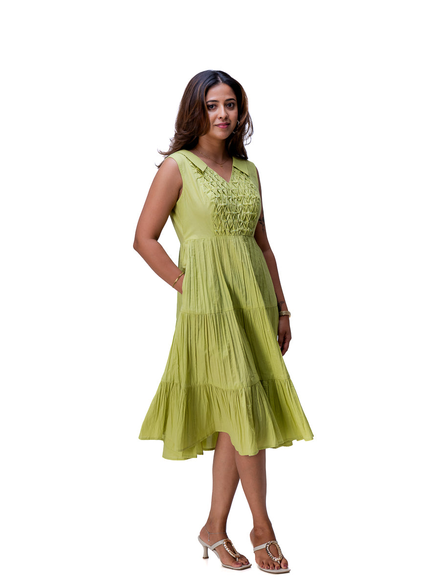 A woman modeling a sleeveless tiered midi dress in a Dahlia Green color with embroidered detailing on the bodice, set against a plain white background.
